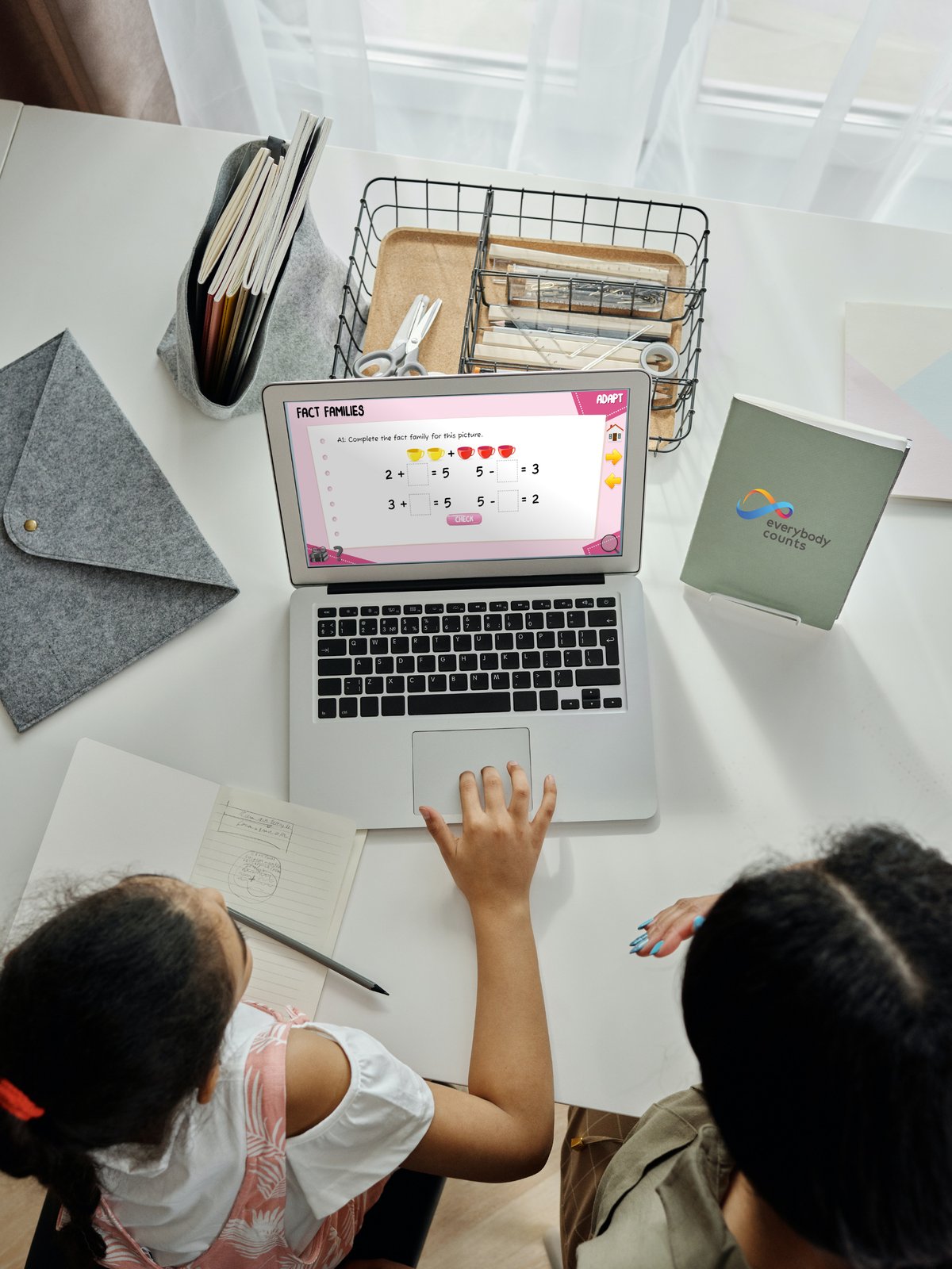 Two pupils working with the Everybody Counts platform alongside a branded notebook