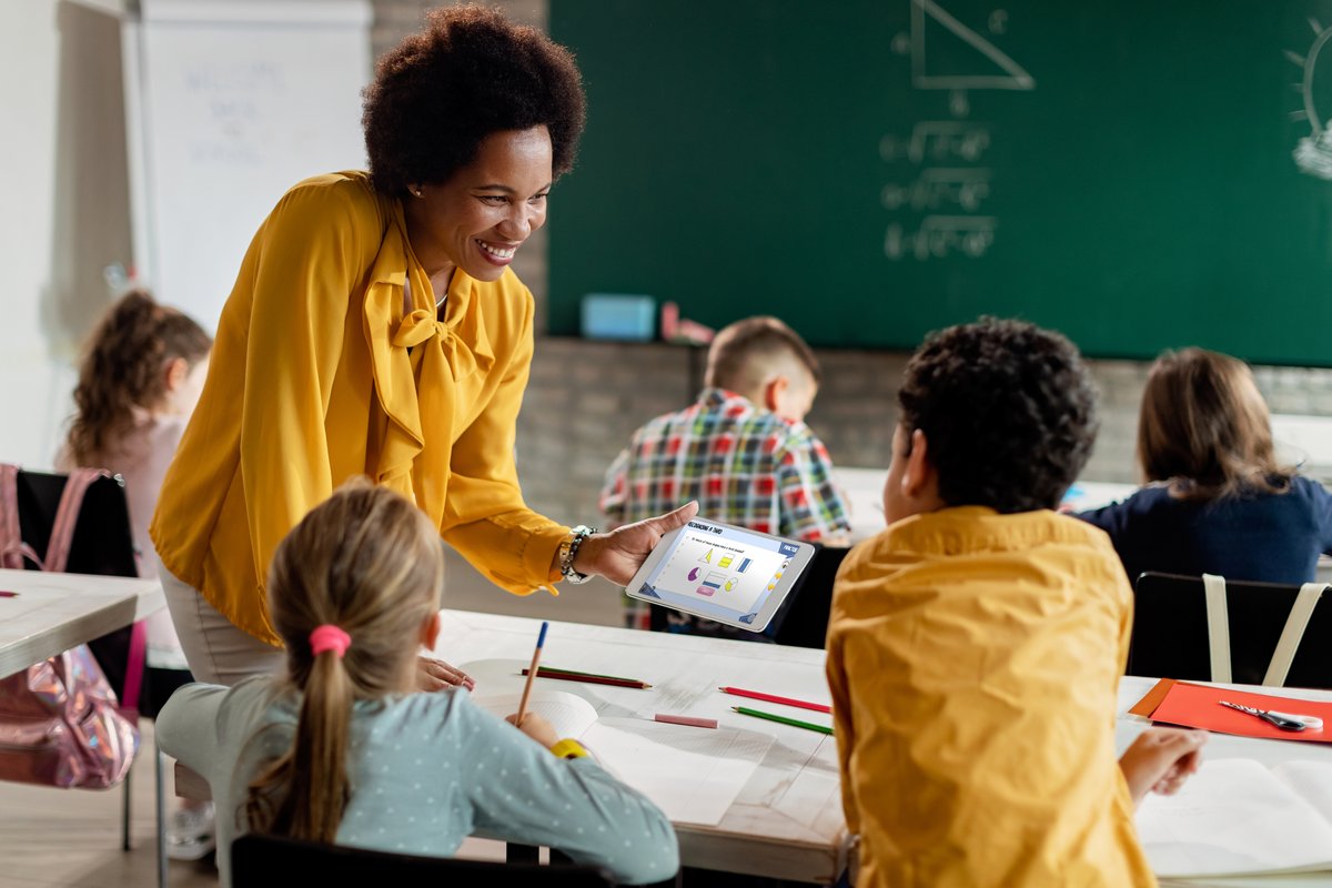 A teacher in the classroom showing pupils the Everybody Counts platform on a tablet
